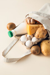 Eco bag with different products and bottle of milk on light background, closeup