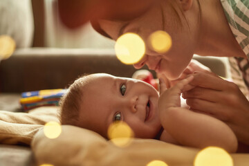 Laughing baby enjoying mother's gentle touches, closeup portrait