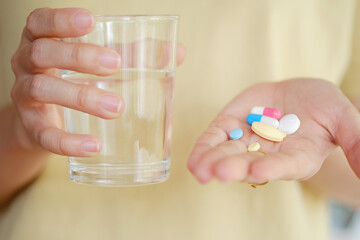 Medicine and water in a woman's hand for eating to treat sickness. Health care concept.