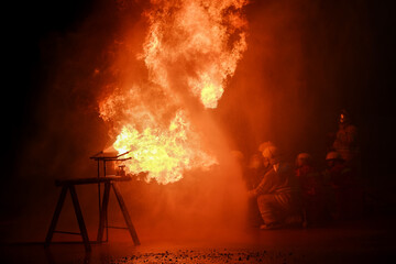 Firefighters are extinguishing the blazing fire at night.