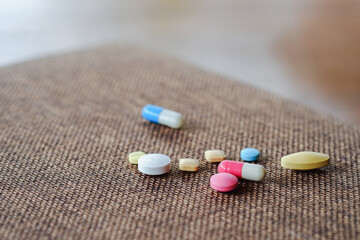 Fototapeta na wymiar Pills and capsules stacked on brown background. Health care concept.