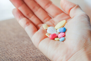 Close-up of a group of pills in a woman's hand with blurred background. Health care concept.