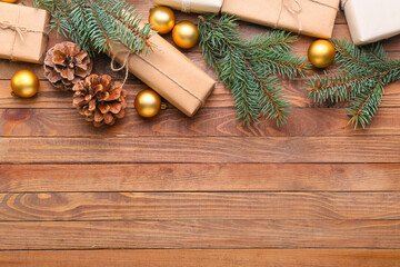 Christmas gifts with fir branches, cones and balls on wooden background