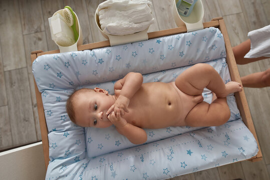 Naked baby boy on nursery pad, top view