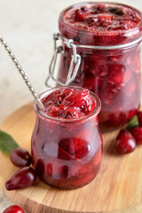 Jars with delicious dogwood jam on table, closeup