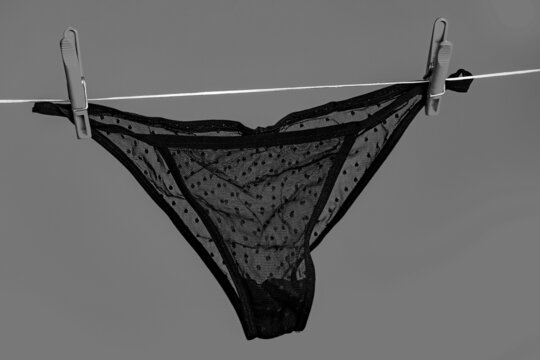 Black panties. Lingerie. Female lace lingerie. Womans black erotic panties. Women's panties hanging on rope isolated on black background.