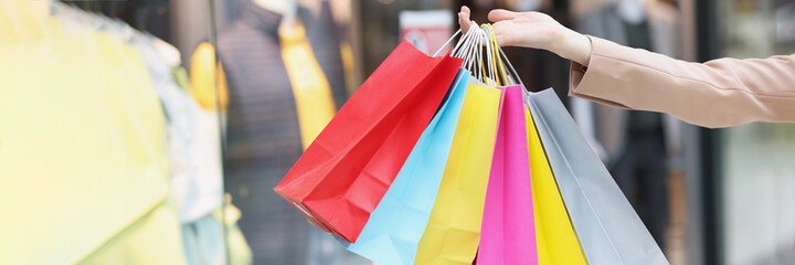 Multicolored paper bags on female hands on background of shopping mall