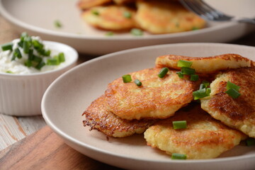 Potato pancakes or latkes or draniki with sour cream in plate on wooden table.
