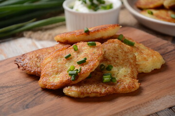 Potato pancakes or latkes or draniki with sour cream in plate on wooden table.
