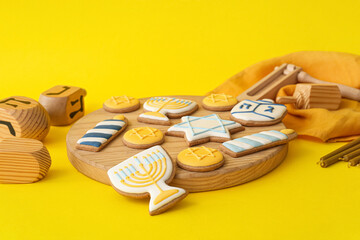 Board with tasty cookies for Hanukkah celebration on color background