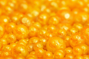 Beautiful background with pearl gold pearls, top view. Abstract texture for festive backgrounds. Shiny yellow surface of Christmas decorations. Gems close-up. Golden bright background.