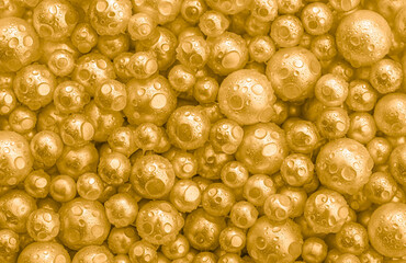 Beautiful background with pearl gold pearls, top view. Abstract texture for festive backgrounds. Shiny yellow surface of Christmas decorations. Gems close-up. Golden bright background.