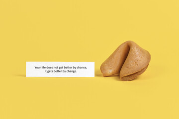 Fortune cookie note saying 'Life does not get better by chance, it gets better by change' on yellow...