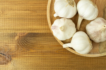 Whole garlic heads on wooden table top view with copy space.