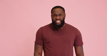 Young African american man get mad show teeth on pink background
