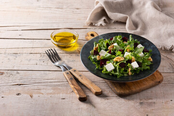 Beetroot salad with feta cheese,lettuce and walnuts on rustic wooden table.Copy space