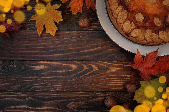 Autumn background with pumpkin cake, maple leaves, aples and acorns. Top view. Copy space