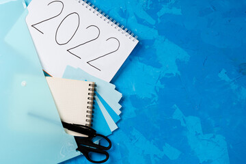 New Year resolution Goal list 2022 on blue background with notebook and chansellery