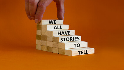 We all have stories to tell symbol. Wooden blocks with words 'We all have stories to tell'. Businessman hand. Beautiful orange background. Business, popular quotation concept. Copy space. - obrazy, fototapety, plakaty