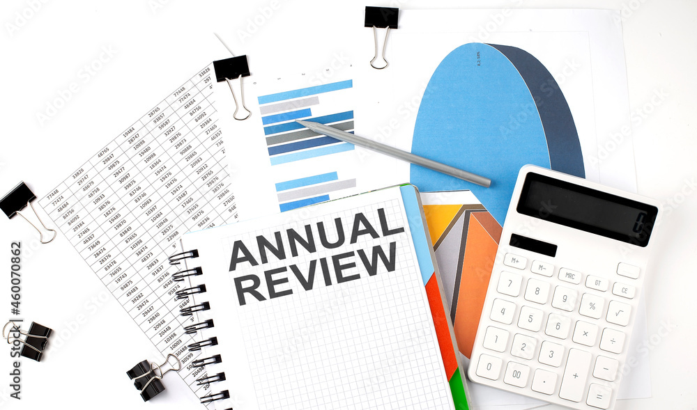 Poster text annual review on a notebook on the diagram and charts with calculator and pen