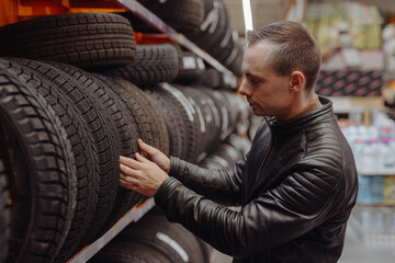 Fototapeta na wymiar Man chooses winter car tires in the auto shop