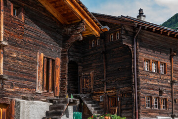Weathered old wooden vintage house in Swiss Alps. View of green meadow in mountains from typical wooden house village in beautiful springtime.