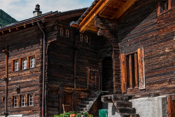 Fototapeta na wymiar Weathered old wooden vintage house in Swiss Alps. View of green meadow in mountains from typical wooden house village in beautiful springtime.