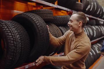 Naklejka na ściany i meble Man chooses winter car tires in the auto shop