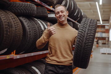 Naklejka na ściany i meble Man chooses winter car tires in the auto shop