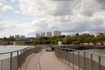 Bridge over the city lake. Park pier on the water. View of the city.