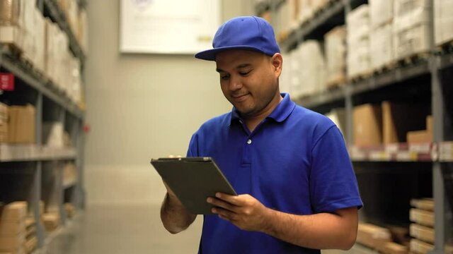Supply chain. Young worker in blue uniform checklist manage parcel box product in warehouse. Asian man employee using tablet working at store industry. Distribution warehouse Logistic import export