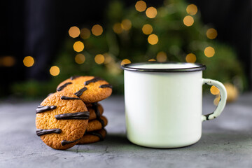 orange cookies with black stripes and cup of tea with fir tree branch. Christmas dessert. Concept for children new year