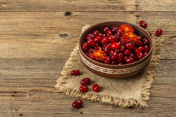Ripe dogwood berry with bright marigold flowers on old wooden table