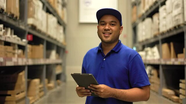 Supply chain. Young worker in blue uniform checklist manage parcel box product in warehouse. Asian man employee using tablet working at store industry. Distribution warehouse Logistic import export