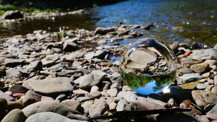 Lensball photography with a crystal ball in the sunlight on a stone bank of a river
