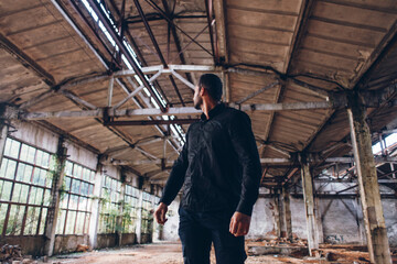 Naklejka na ściany i meble Handsome Man in Black Jacket in Dark Empty Abadoned Factory Hall 