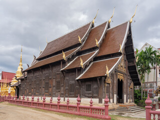 Side view of beautiful ancient wooden Wat Phan Tao buddhist temple with golden stupa, Chiang Mai,...
