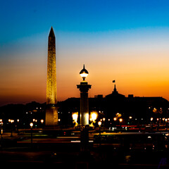Fototapeta na wymiar Obélisque, Place de la Concorde à Paris, un soir de coucher de soleil bleu orangé, avec le Grand Palais en arrière-plan. 