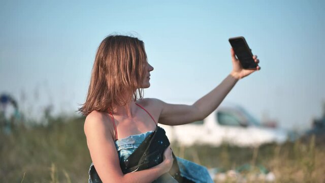 The girl takes a selfie on the city beach.