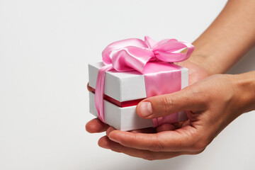 Female hands holding small gift box with ribbon on white background