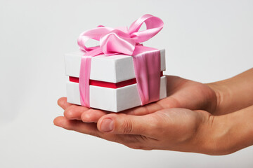 Female hands holding small gift box with ribbon on white background