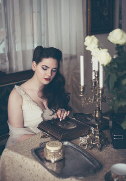 Young woman looks at a photo album. Vintage style, retro interior.