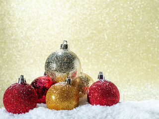 Christmas balls in the snow on a background of golden glitter.