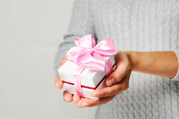 Woman hands holding small gift box with ribbon