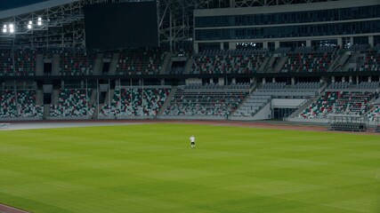 Obraz premium WIDE Caucasian pre teen kid boy entering the field of huge soccer stadium, holding a ball, dreaming of becoming professional player, soccer star