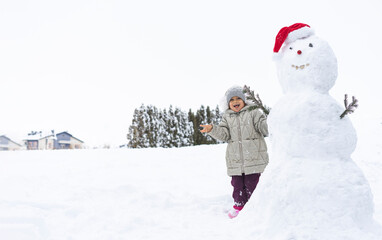 Fototapeta na wymiar child builds a snowman in the winter in the yard. concept of winter games with snow for children