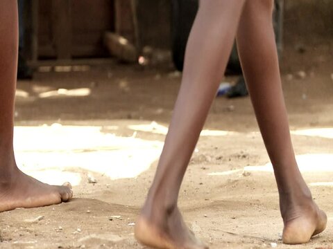African girls play rubber band jumping. Close up of their bare feet.