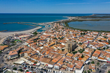 Fototapeta premium Drohnenaufnahme, Drohnenfoto von Saintes-Maries-de-la-Mer mit Altstadt, Hafen, die Kirche Notre Dame&nbsp;und die Salzfelder im Hintergrund, Département Bouches-du-Rhône, Provence, Côte d’Azur, Frankreich