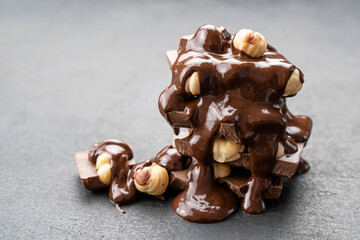 melted chocolate spread with hazelnut on black background. Chocolate tower covered with topping....