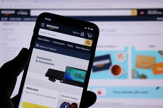 Amazon application on smartphone screen and Amazon website background on computer screen. - Chiang Mai, Thailand September 26, 2021